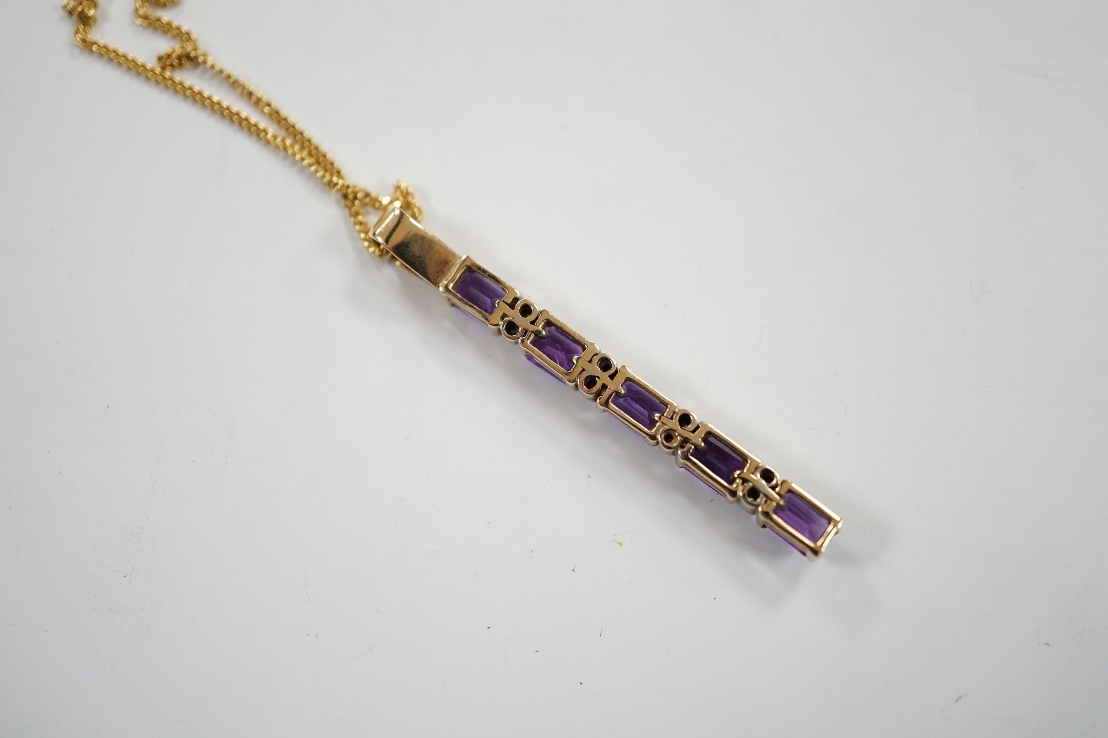 A modern yellow metal, amethyst and diamond chip set line pendant, 47mm, on an 18ct gold fine link chain, 38cm, gross weight 6.4 grams. Fair condition.